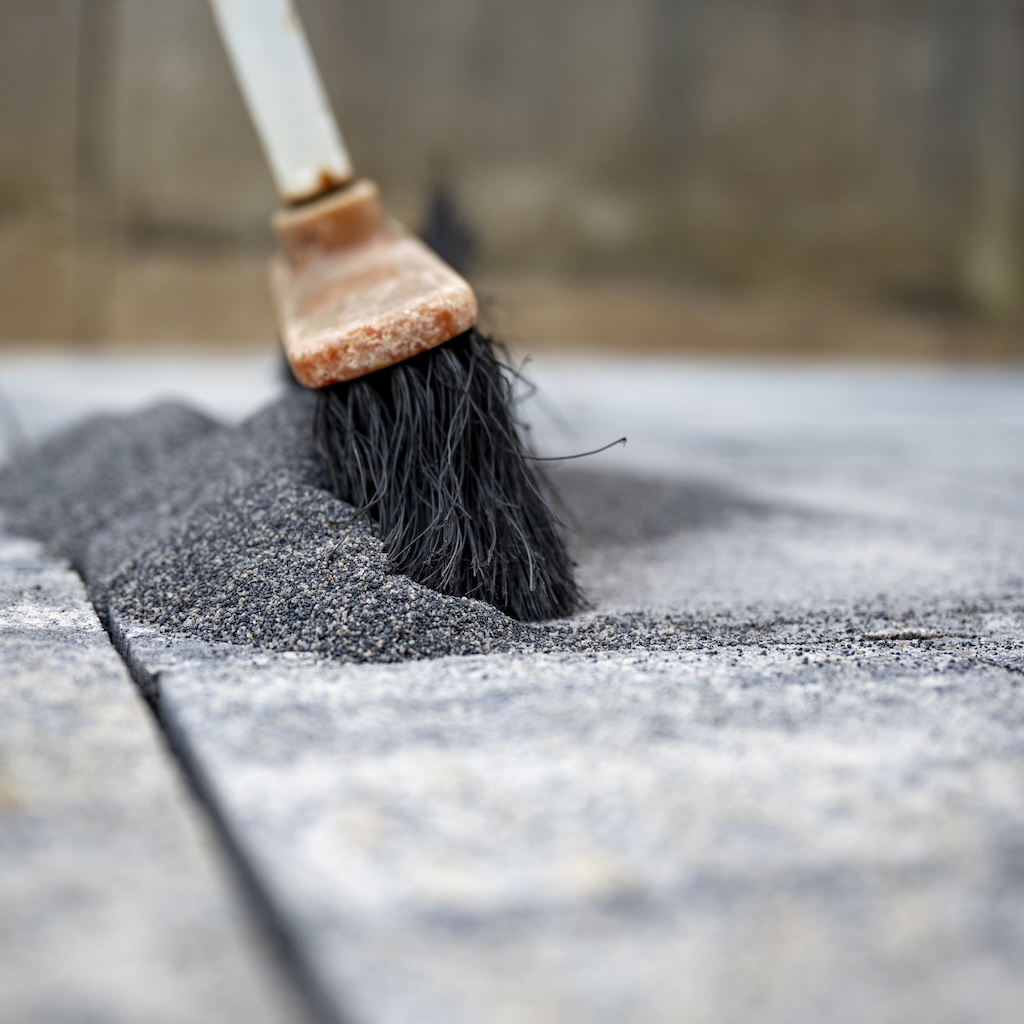 broom-pushing-a-tile-gaps-sand-in-between-concrete-2025-02-19-05-16-47-utc